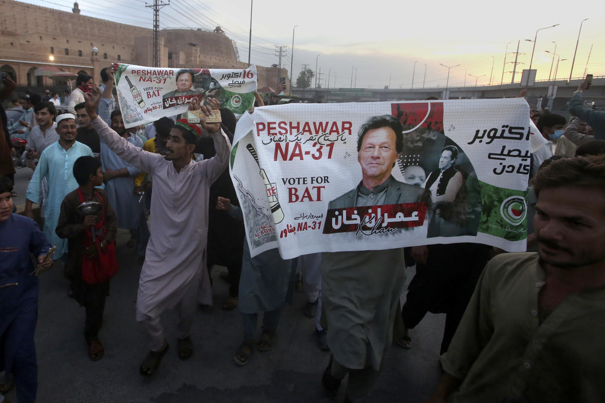 Supporters of Pakistan's former Prime Minister Imran Khan celebrate, holding a banner showing Imran Khan that says: Peshawar NA-31, Vote for BAT. 