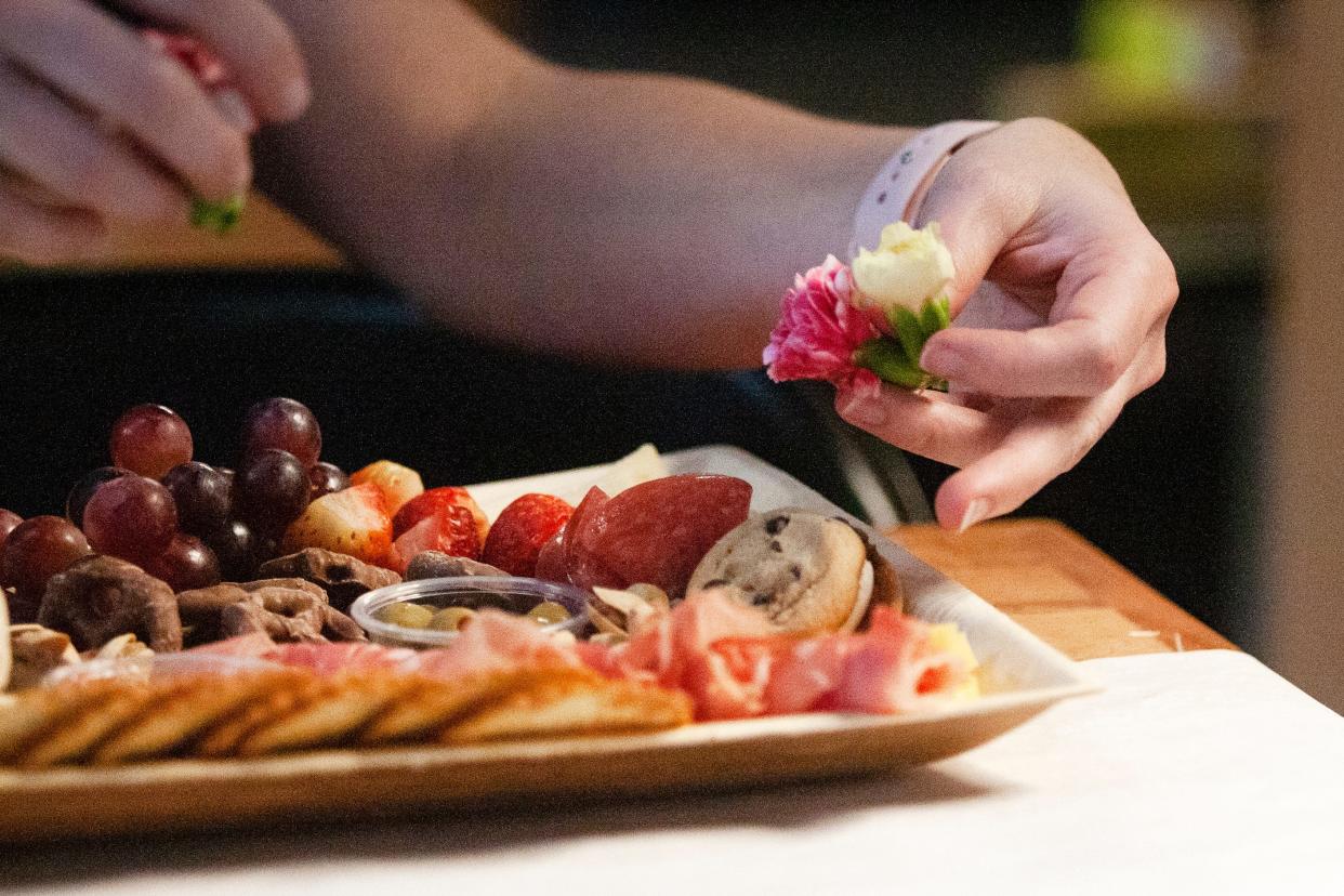 Participants arrange flower and rose garnishes on their boards during a charcuterie class on at Smash Park in West Des Moines.