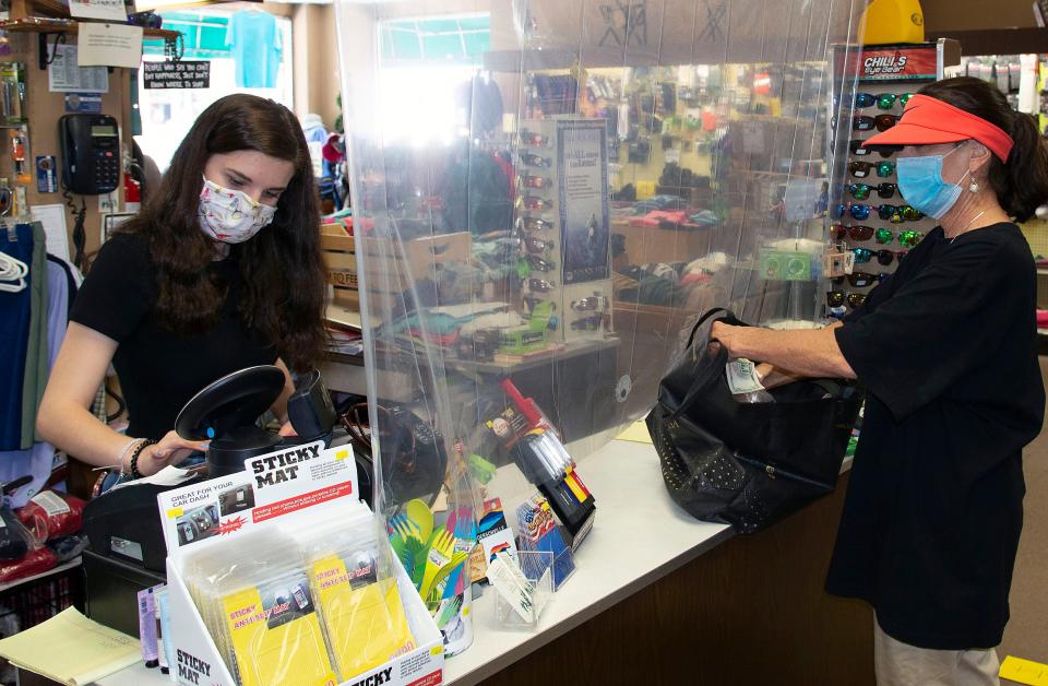 Sherman's Sports and Army Store worker Becca Chamberlain rrings up customer Ruth Benson of Charlotte during the first hour of the Open Streets event in downtownn Hendersonville May 30, 2020. Store owner Becky Banadyga placed a sign on the front door asking customers to wear face coverings to protect themselves and others from COVID-19 infection