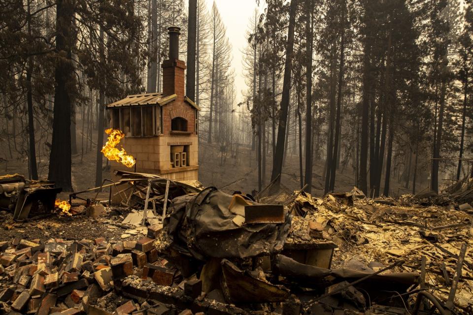 Propane gas flames leap from a broken pipe amid the rubble of a burned-out home.