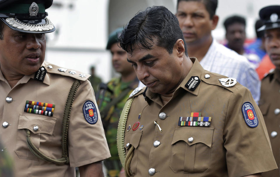 In this April 21, 2019 photo, Sri Lankan police chief Pujith Jayasundara, right, leaves after an inspection at St. Anthony's church, one of the sites of Easter Sunday explosions in Colombo, Sri Lanka. Sri Lankan police on Tuesday arrested the country's police chief, currently on compulsory leave, and its former defense secretary for alleged negligence leading to the Easter Sunday bombings that killed more than 250 people at churches and hotels. (AP Photo/Eranga Jayawardena)