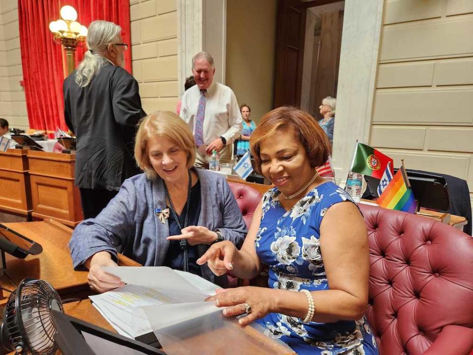  Rhode Island state Reps. Mary Ann Shallcross Smith, left, and Grace Diaz, both Democrats, confer this month over the proposed budget, which includes funding of a program to subsidize child care for caretakers’ kids. (Elaine S. Povich/Stateline)