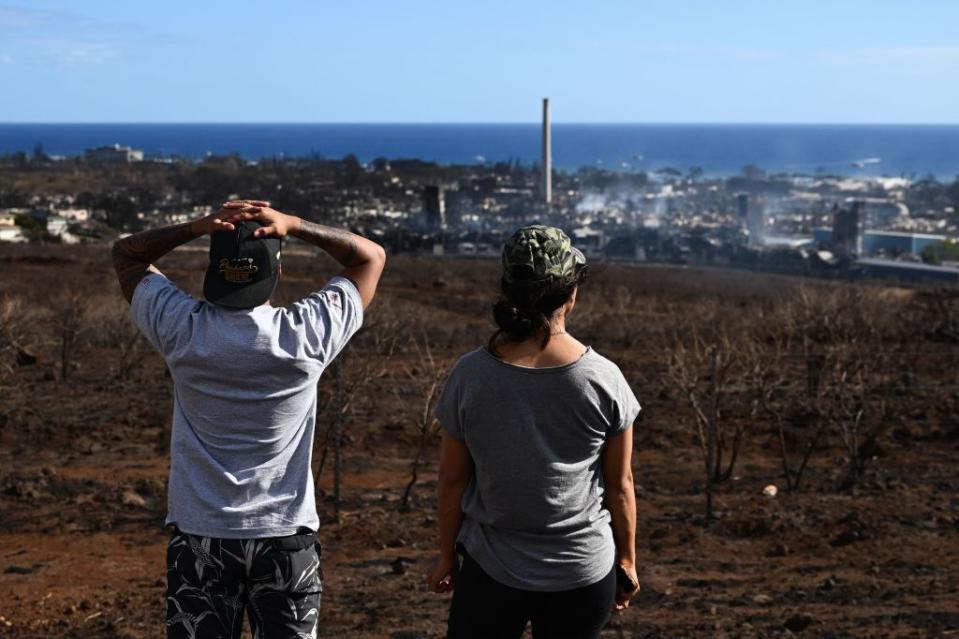 Maui residents John Rey Serrano and Lexie Lara look from a road above Lahaina Town in the aftermath of a wildfire in Lahaina, western Maui, Hawaii.