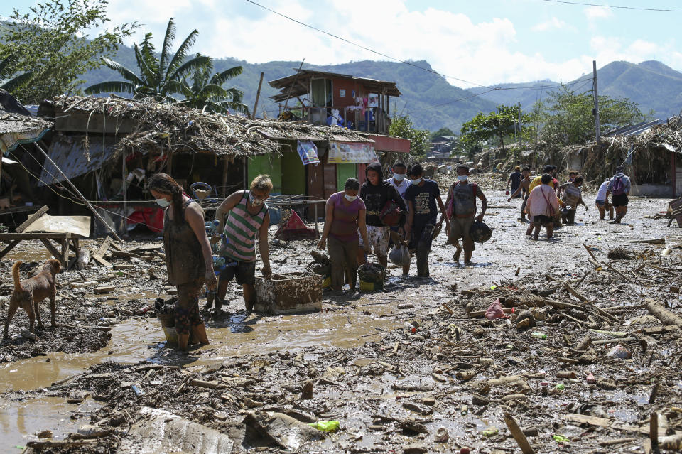 Residents walk through mud and debris as they return to retrieve belongings from the typhoon-damaged Kasiglahan village in Rodriguez, Rizal province, Philippines on Friday, Nov. 13, 2020. Thick mud and debris coated many villages around the Philippine capital Friday after Typhoon Vamco caused extensive flooding that sent residents fleeing to their roofs and killing dozens of people. (AP Photo/Aaron Favila)