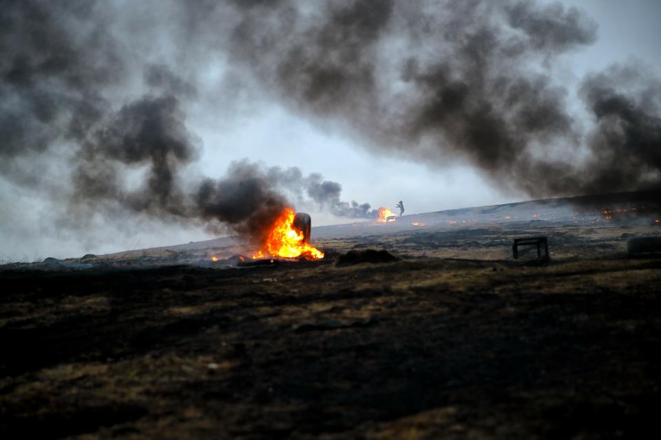 In this photo taken on Sunday, March 10, 2019, a child spins a burning tire on a metal chain, during a ritual marking the upcoming Clean Monday, the beginning of the Great Lent, 40 days ahead of Orthodox Easter, on the hills surrounding the village of Poplaca, in central Romania's Transylvania region. Romanian villagers burn piles of used tires then spin them in the Transylvanian hills in a ritual they believe will ward off evil spirits as they begin a period of 40 days of abstention, when Orthodox Christians cut out meat, fish, eggs, and dairy. (AP Photo/Vadim Ghirda)