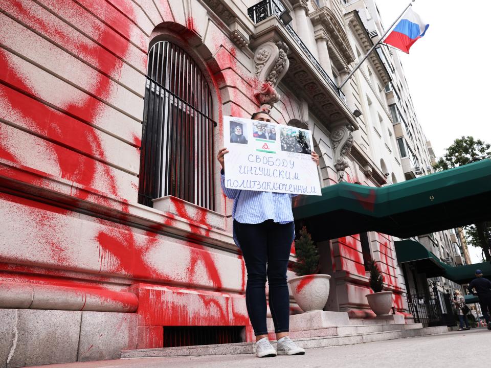 A woman holds a protest sign as she stands in front of a vandalized Russian Consulate on September 30, 2022 in New York City.