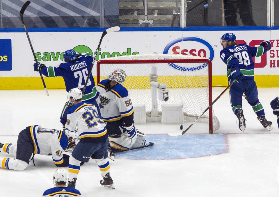 Vancouver Canucks' Antoine Roussel (26) and Adam Gaudette (88) celebrate a goal against St. Louis Blues goalie Jordan Binnington (50) during second-period NHL Western Conference Stanley Cup playoff hockey game action in Edmonton, Alberta, Friday, Aug. 21, 2020. (Jason Franson/The Canadian Press via AP)