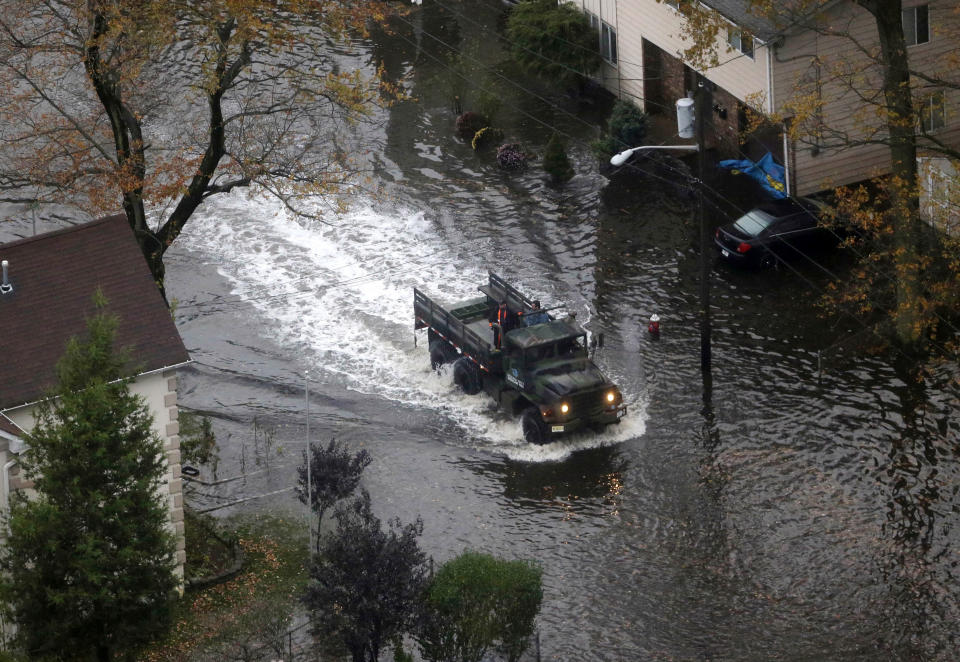 An emergency vehicle drives on a flooded street in Little Ferry, N.J. in the wake of superstorm Sandy on Tuesday, Oct. 30, 2012. Sandy, the storm that made landfall Monday, caused multiple fatalities, halted mass transit and cut power to more than 6 million homes and businesses. (AP Photo/Mike Groll)