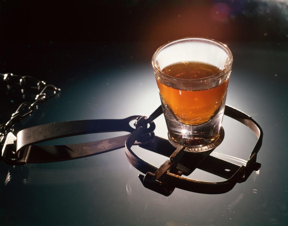 SHOT GLASS OF ALCOHOLIC LIQUOR BAITING A STEEL TRAP