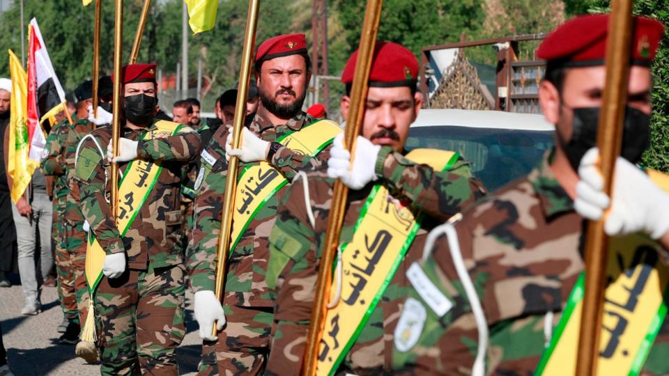 PHOTO: Fighters lift flags of Iraq and paramilitary groups, including al-Nujaba and Kataib Hezbollah, during a funeral in Baghdad for five militants killed a day earlier in a US strike in northern Iraq, Dec. 4, 2023.  (Ahmad Al-rubaye/AFP via Getty Images)