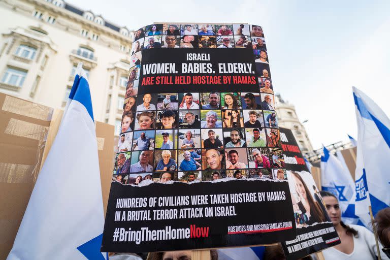Una persona sujeta un cartel con los rostros de las personas secuestradas durante una manifestación por la liberación de los rehenes secuestrados por Hamas, frente al Congreso de los Diputados, a 22 de octubre de 2023, en Madrid, España