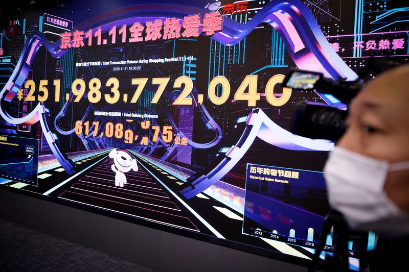 FILE PHOTO: A camera man films a screen showing JD's total transaction volume and total delivery distance at the data room of JD.com's headquarters on China's Singles Day shopping festival in Beijing