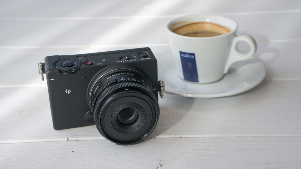 Sigma fp on a table next to an expresso coffee cup