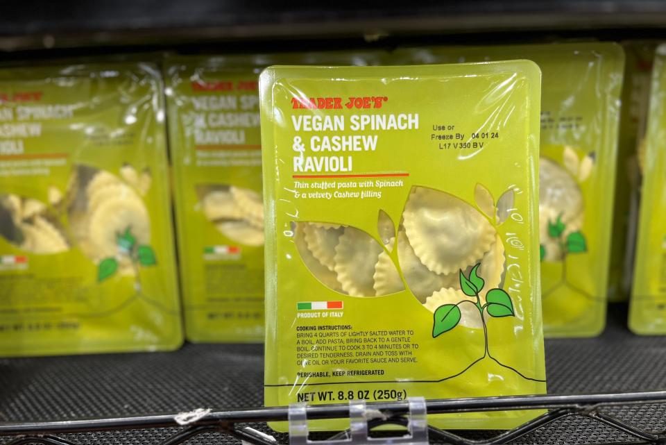 A green box of Trader Joe's vegan spinach and cashew ravioli on a black shelf at Trader Joe's