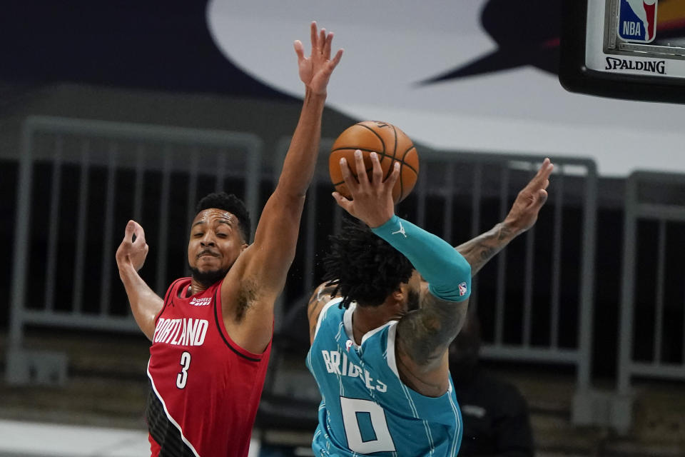 Charlotte Hornets forward Miles Bridges dunks past Portland Trail Blazers guard CJ McCollum during the first half in an NBA basketball game on Sunday, April 18, 2021, in Charlotte, N.C. (AP Photo/Chris Carlson)