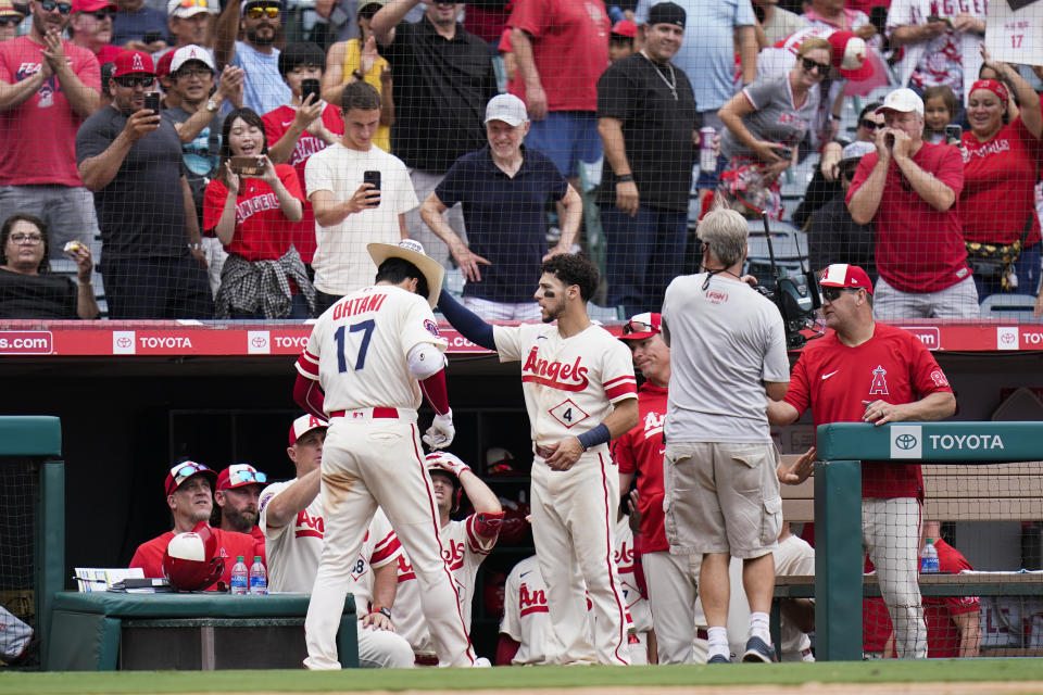 Fans cheer as Los Angeles Angels' Andrew Velazquez (4) puts a cowboy hat onto Shohei Ohtani (17) after Ohtani's second home run of the baseball game, during the seventh inning against the Oakland Athletics on Thursday, Aug. 4, 2022, in Anaheim, Calif. (AP Photo/Jae C. Hong)
