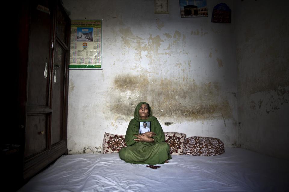 In this Tuesday, March 18, 2014 photo, Pakistani Salima Akhtar, 65, mother of Akmal Omar, 21, who was one of eleven victims that was killed by suicide bombers in an attack on a court complex on the 3rd of March 2014, grieves while embracing his photograph in his bedroom, in Rawalpindi, Pakistan. "They ripped my heart from my chest, how can I live after you my Akmal," Salima said. (AP Photo/Muhammed Muheisen)