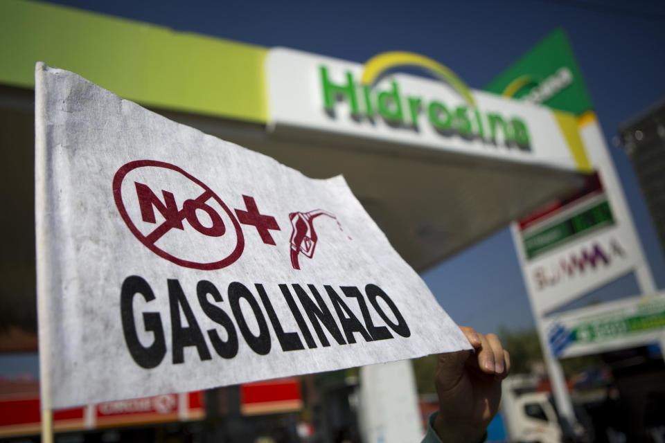 A protester holds a flag that says in Spanish "No more gasoline price hikes" during an hours-long blockade of one of the city's oldest gas stations, at a main intersection in Mexico City, Monday, Jan. 2, 2017. Protesters are blocking roads and stations across Mexico to protest a government price deregulation that sent the price of fuel up by as much as 20 percent over the weekend. (AP Photo/Rebecca Blackwell)