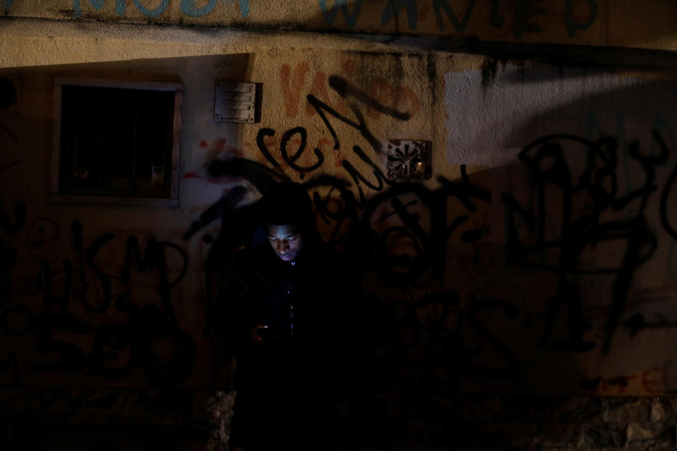 A man checks his phone on a street in Cova da Moura 