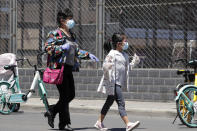 A woman and a child wearing protective face masks and gloves to help curb the spread of the new coronavirus arrive to a stadium to get a nucleic acid test in Beijing, Sunday, June 14, 2020. China is reporting its highest daily total of coronavirus cases in two months after the capital's biggest wholesale food market was shut down following a resurgence in local infections. (AP Photo/Andy Wong)