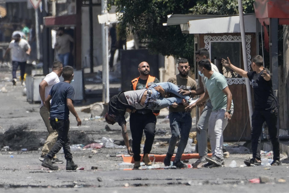 Palestinians carry a wounded man shot by Israeli fire shortly after he threw a bomb toward an Israeli army vehicle during a military raid in the Jenin refugee camp, a militant stronghold in the occupied West Bank, Tuesday, July 4, 2023. Palestinian health officials said several Palestinians were killed and dozens wounded in the operation, which Israeli forces launched Monday. (AP Photo/Majdi Mohammed)