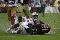 Rain water splashes as San Francisco 49ers cornerback Jimmie Ward (20) tackles Washington Redskins running back Wendell Smallwood in the first half of an NFL football game, Sunday, Oct. 20, 2019, in Landover, Md. (AP Photo/Alex Brandon)