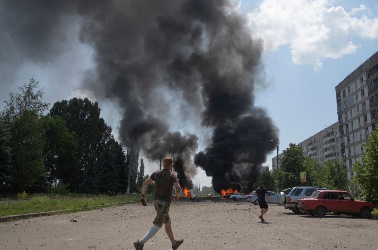 Locals react at the scene of a rocket attack on the Pervomaiskyi settlement of the Kharkiv area (EPA)