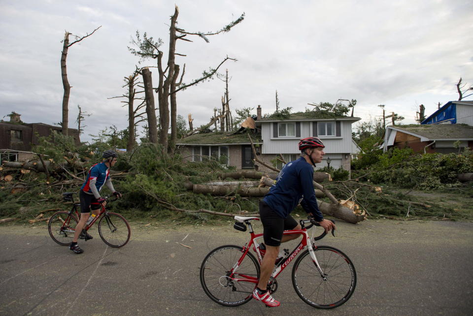 <p>People cycle past homes damaged by trees by a tornado in the Arlington Woods neighbourhood of Ottawa, on Sunday, Sept. 23, 2018. The storm tore roofs off of homes, overturned cars and felled power lines in the Ottawa community of Dunrobin and in Gatineau, Que. A second tornado also hit the Nepean neighbourhood of Arlington Woods. (Photo from Justin Tang/The Canadian Press) </p>