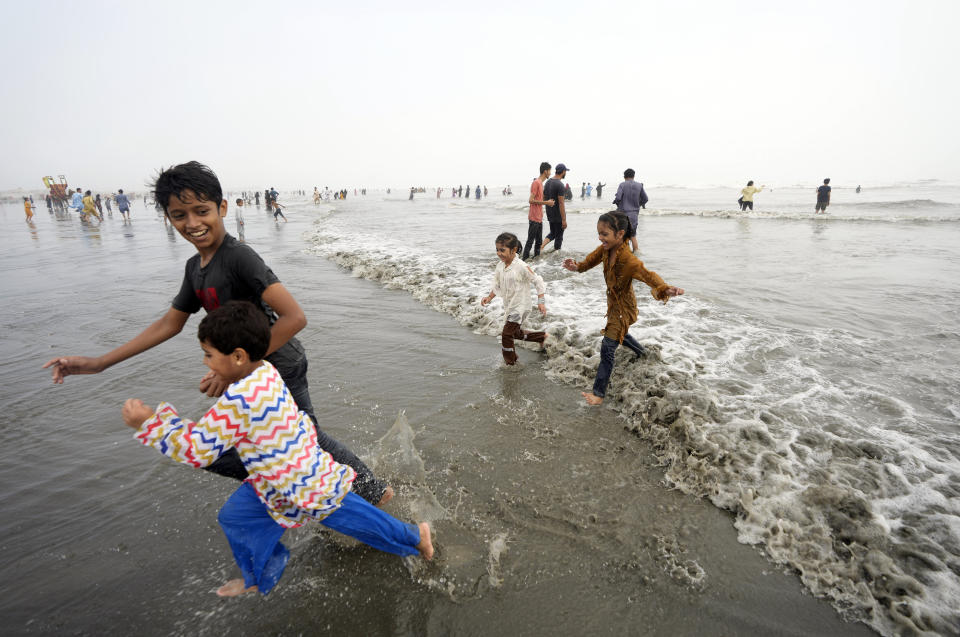 Children enjoy high tide waves on the Clifton beach, during a heat wave in Karachi, Pakistan, Thursday, July 25, 2024. (AP Photo/Fareed Khan)
