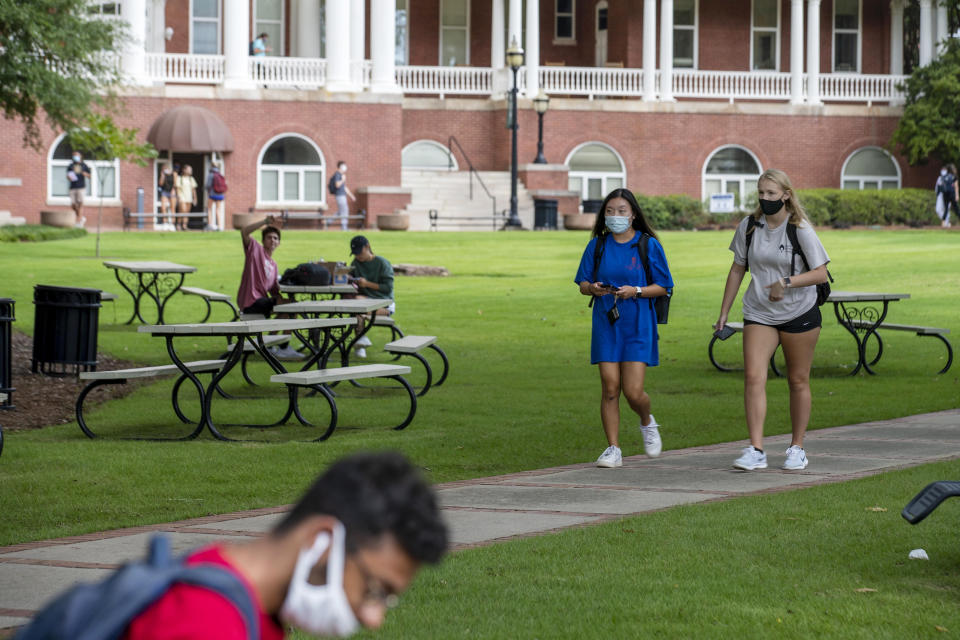 FILE - In this Aug. 21, 2020, file photo, Georgia College and State University freshmen Ashlynn Anglin, right, and Meghan Murphy, second from right, wear face masks as they talk while walking through the campus in Milledgeville, Ga. As more and more schools and businesses around the country get the OK to reopen, some college towns are moving in the opposite direction because of too much partying and too many COVID-19 infections among students. (Alyssa Pointer/Atlanta Journal-Constitution via AP, File)