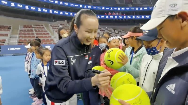 Chinese tennis player Peng Shuai signs large-sized tennis balls at the opening ceremony of Fila Kids Junior Tennis Challenger Final in Beijing