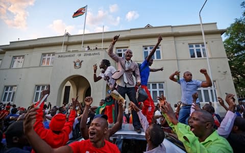 Zimbabweans celebrate outside the parliament building immediately after hearing the news that President Robert Mugabe had resigned - Credit:  Ben Curtis/ AP