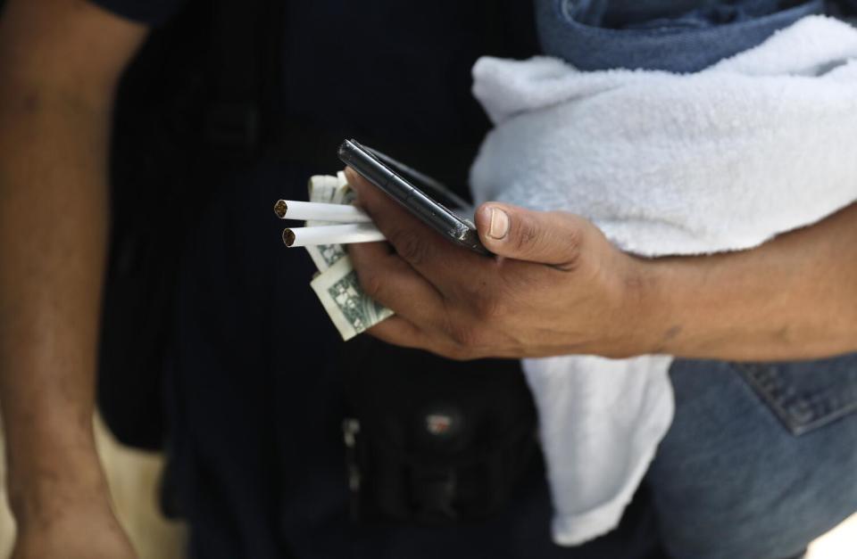 A man holds cigarettes and money.