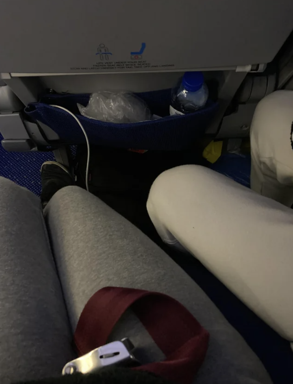 a man's legs in someone else's leg space on a plane