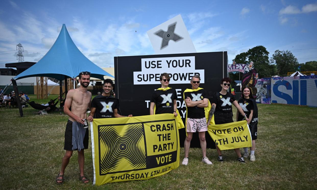 <span>A stall is set up at Glastonbury urging people to vote – the activists joined by green energy entrepreneur Dale Vince, centre.</span><span>Photograph: Dylan Martinez/Reuters</span>