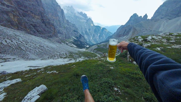 Person holding beer stein with mountains in background