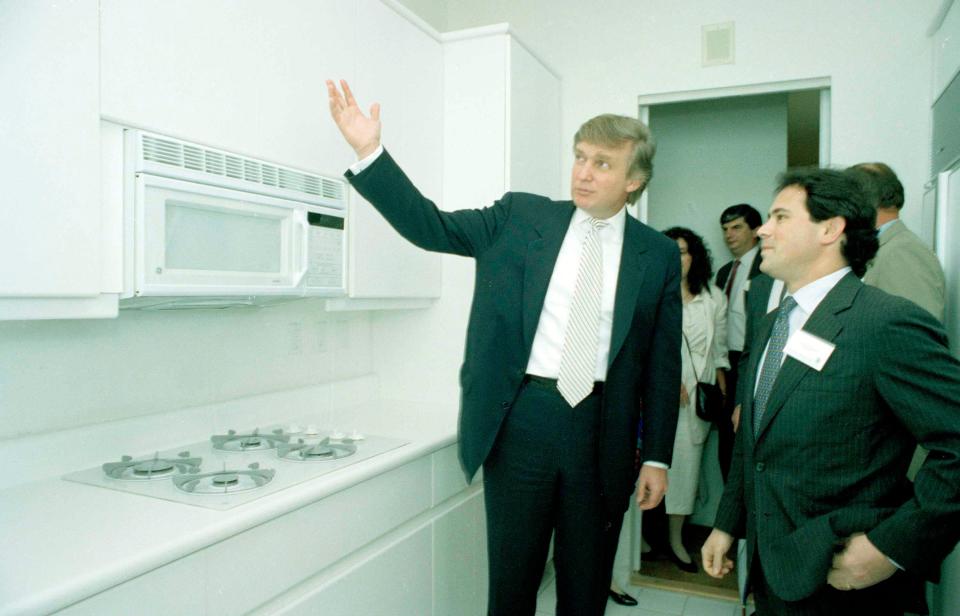 A 1990's photograph of Donald Trump showing off an all-white kitchen in the new Trump Palace apartments.