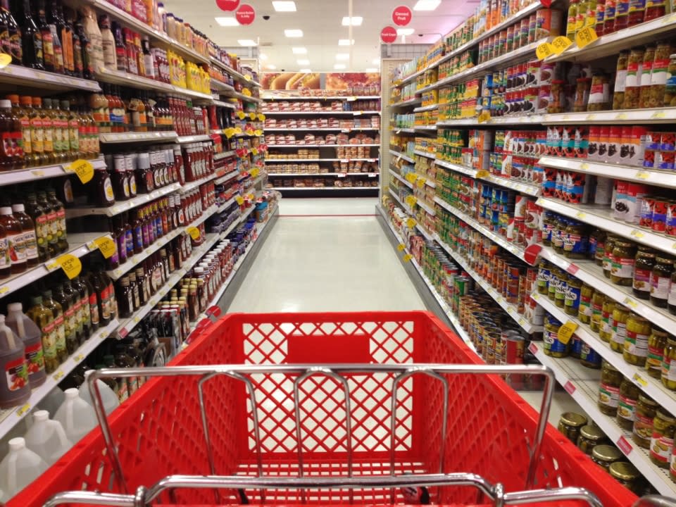 A red shopping cart in the middle of a food aisle in Target.