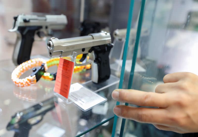 A Hungarian vendor shows an Ekol Firat Magnum gas pistol at a gun shop where people queued up to buy weapons for protection during the coronavirus pandemic, in Budapest