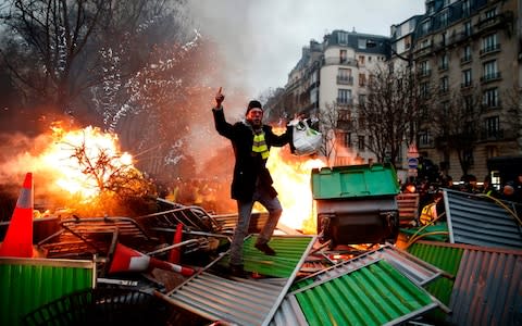A yellow vest protester at a burning barricade in Paris on January 5, 2019 - Credit: &nbsp;ABDULMONAM EASSA/AFP