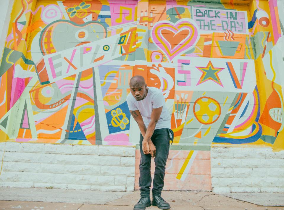 Kedrick Mack, a.k.a. Dope KNife, in front of a Starland Mural Project piece created by Kevin Bongang.