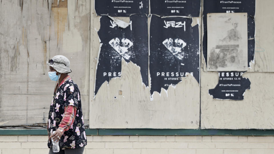 A woman walks past a boarded up business, Thursday, May 28, 2020, in East Cleveland, Ohio. The state says about 1.3 million Ohioans have filed unemployment claims in the past 10 weeks as Ohio's stay-at-home order depressed the economy and led to widespread layoffs. The Ohio Department of Job and Family Services says about 42,000 people filed claims for the week ending May 23. (AP Photo/Tony Dejak)