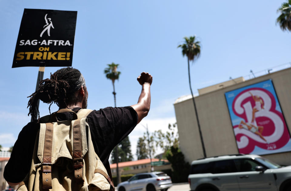 Striking SAG-AFTRA member James Mathis III pickets with other SAG-AFTRA members and striking WGA (Writers Guild of America) workers outside Warner Bros. Studio on July 17, 2023, in Burbank, California.