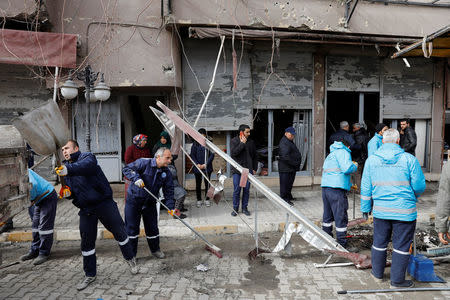Municipality workers clean up a street in front of a building which was hit by rockets fired from Syria, in the border town of Reyhanli in Hatay province, Turkey January 22, 2018. REUTERS/Umit Bektas