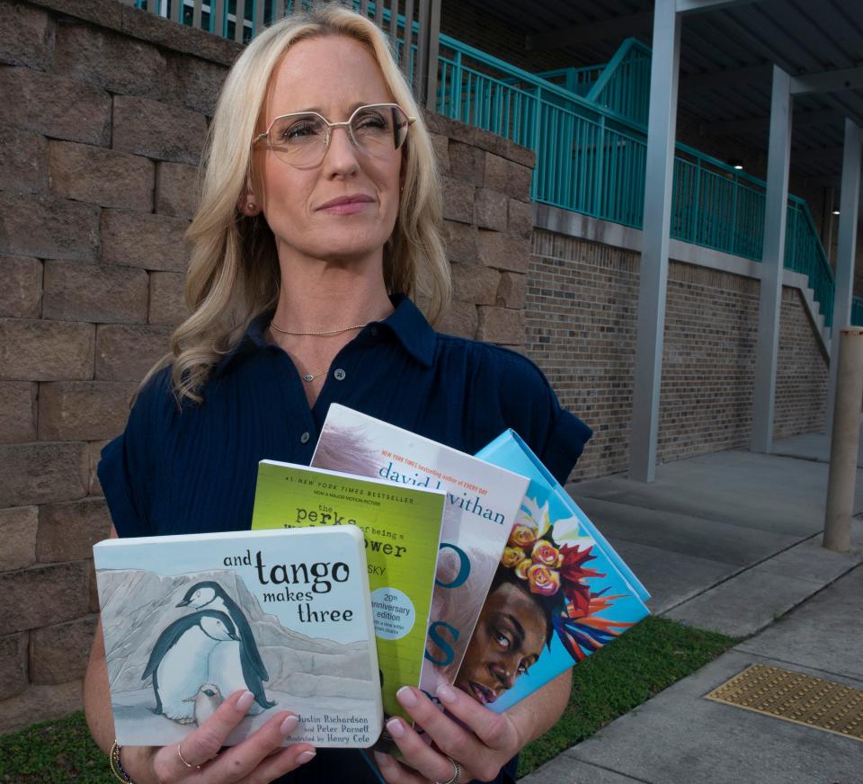 Lindsay Durtschi shows off the books currently banned by the Escambia County school system. Durtschi is part of a lawsuit against the school district and school board over the removal of books from school libraries.