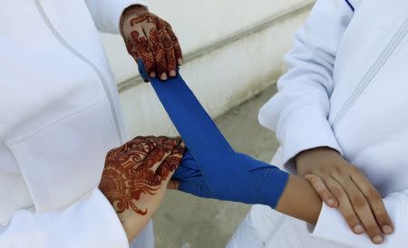 A friend wraps the hand of a boxer competing in the Sindh Junior Sports Association Boxing Tournament in Karachi, Pakistan February 21, 2016. REUTERS/Akhtar Soomro