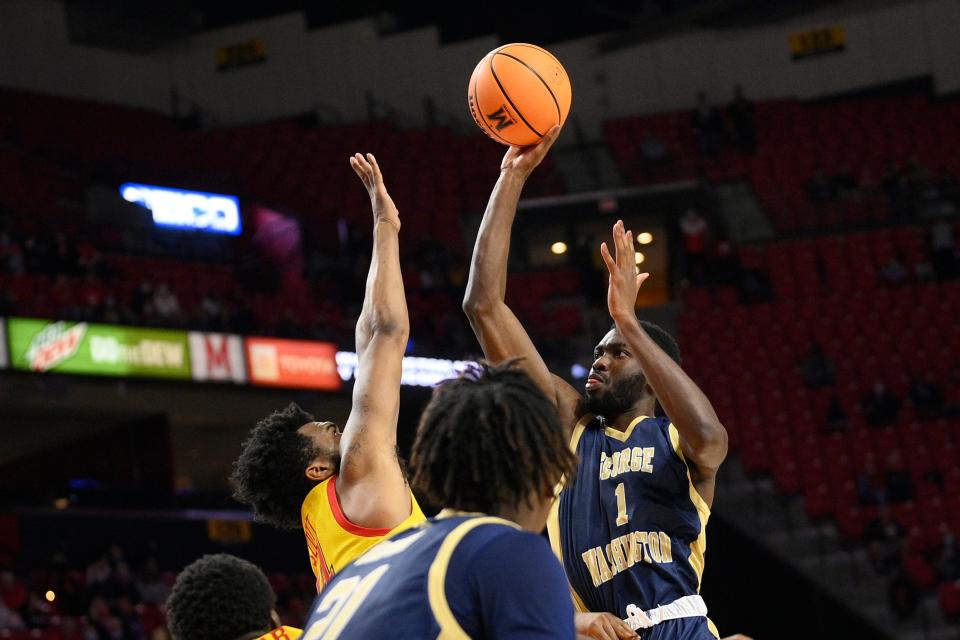 George Washington guard Joe Bamisile (1) shoots against Maryland forward Donta Scott, left, during the first half of an NCAA college basketball game, Thursday, Nov. 11, 2021, in College Park, Md. (AP Photo/Nick Wass)