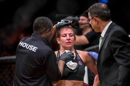 Jul 9, 2016; Las Vegas, NV, USA; Miesha Tate (red gloves) is tended to by medical after being defeating by Amanda Nunes (blue gloves) during UFC 200 at T-Mobile Arena. Nunez won by rear naked choke. Mandatory Credit: Joshua Dahl-USA TODAY Sports