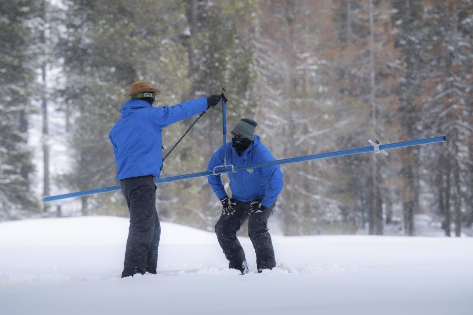 Sean de Guzman, right, snow survey manager for the Department of Water Resources, measures the snow with the help of DWR engineer Jacob Kollen for the final snow survey of the season at Phillips Station on Monday, April 3, 2023. It was the deepest snowpack ever recorded. (Hector Amezcua/The Sacramento Bee via AP)