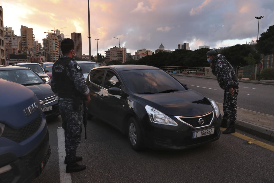 Police officers stand at a checkpoint to inspect cars that violate the lockdown during an 11-day nationwide shutdown aimed at curbing the spread of the coronavirus, in Beirut, Lebanon, Friday, Jan. 15, 2021. Lebanon's parliament has approved a draft law to allow the importing of vaccines into the tiny country to fight the spread of coronavirus. (AP Photo/Bilal Hussein)